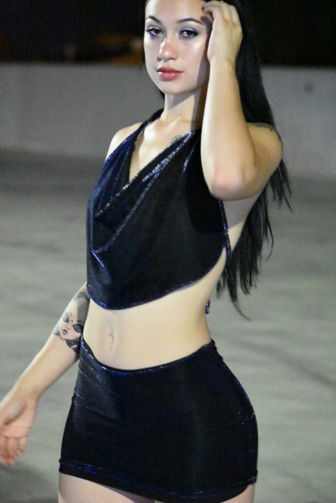 A woman wearing black top and skirt